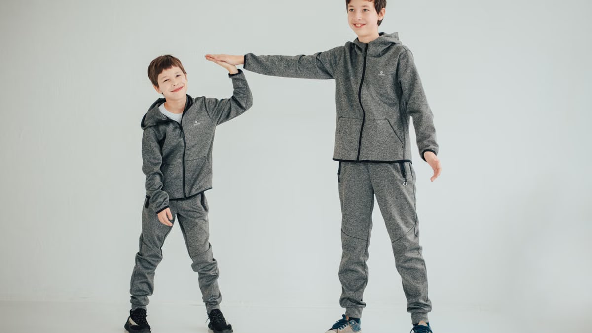 Two brothers sharing a high-five in matching gray outfits on a white background. Studio captured.